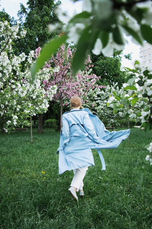 Stylish young woman in garden with blooming trees