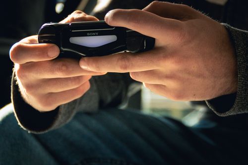 Free A close-up shot of hands gripping a gaming controller indoors with warm lighting. Stock Photo