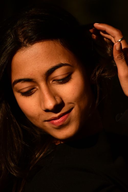 Free A captivating portrait of a young woman with soft lighting, highlighting her serene expression and graceful pose. Stock Photo