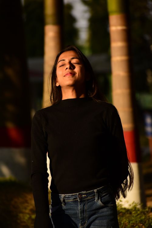 Free A young woman in casual attire enjoying warm sunlight outdoors in India. Stock Photo