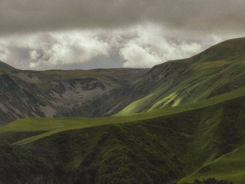 Free Majestic green mountains under a cloudy sky, capturing nature's beauty and serenity. Stock Photo