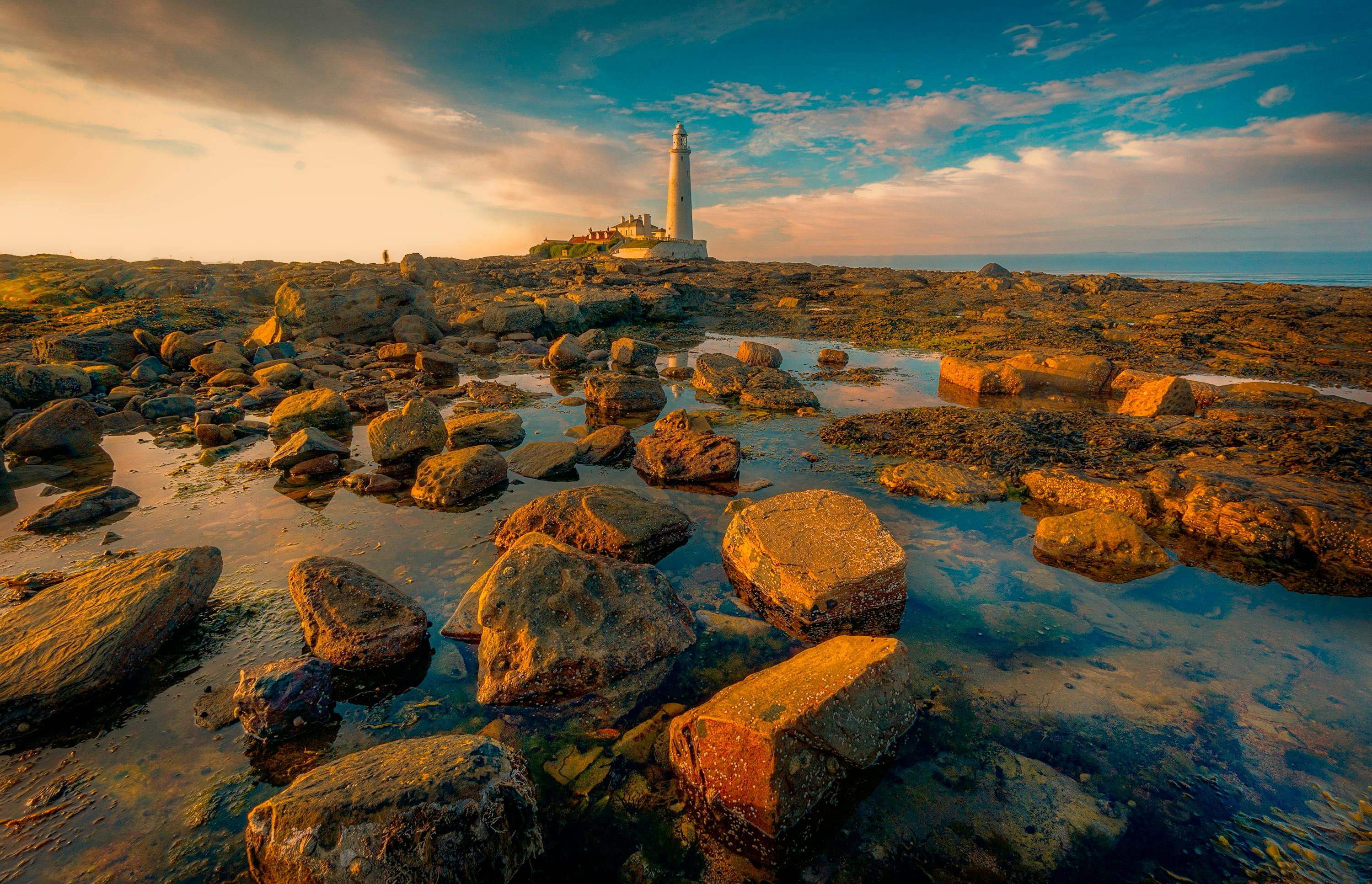 White Lighthouse On Rocky Shore Under Blue Sky · Free Stock Photo