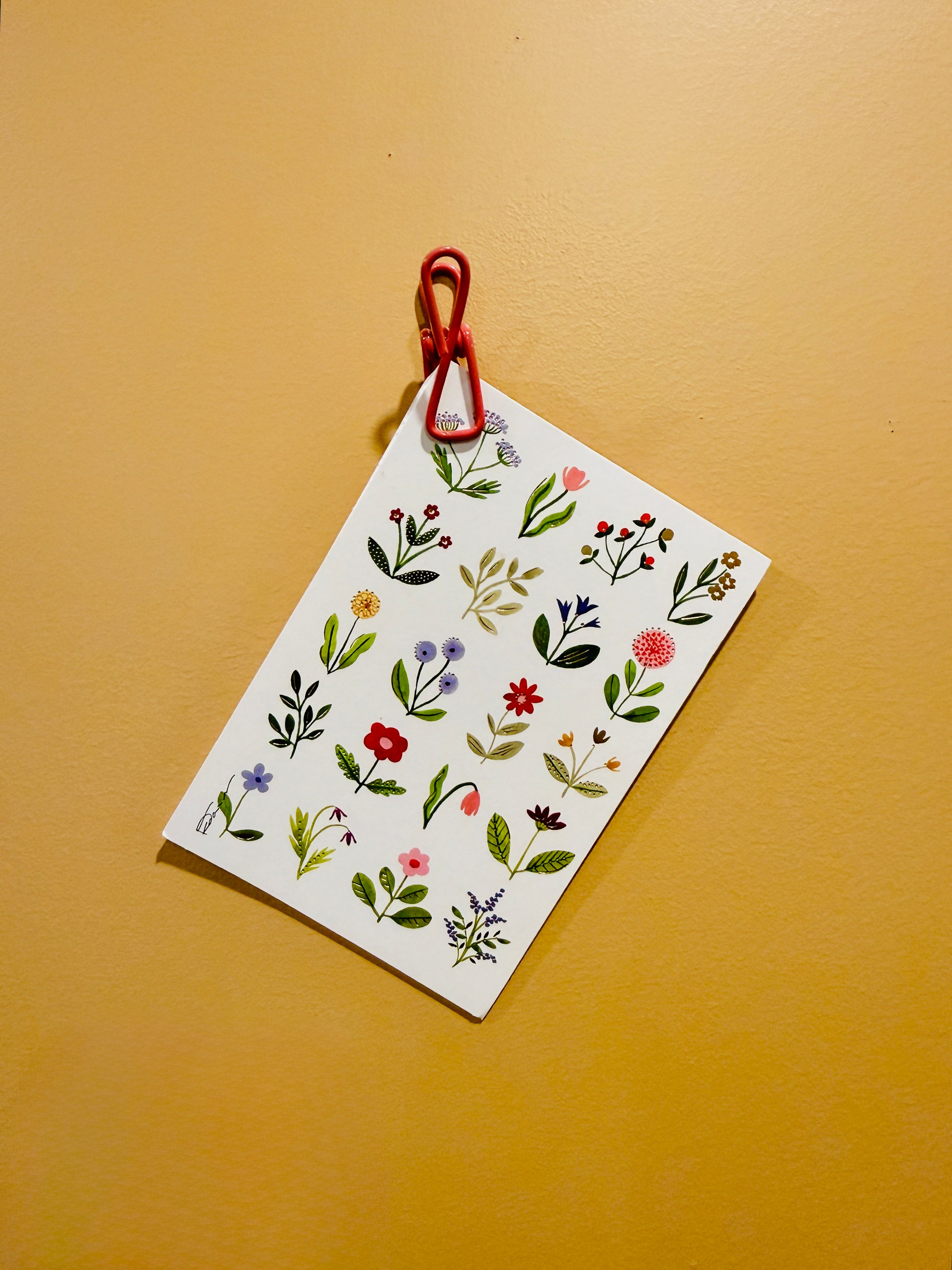 A vibrant floral illustration pinned to a peach wall, showcasing various colorful flowers.