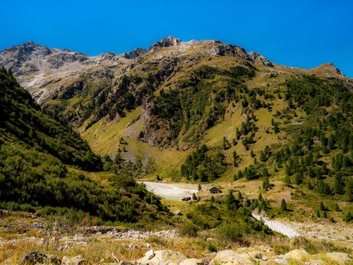 Free Beautiful mountain scenery with lush greenery under a clear blue sky in Bregaglia, Switzerland. Stock Photo