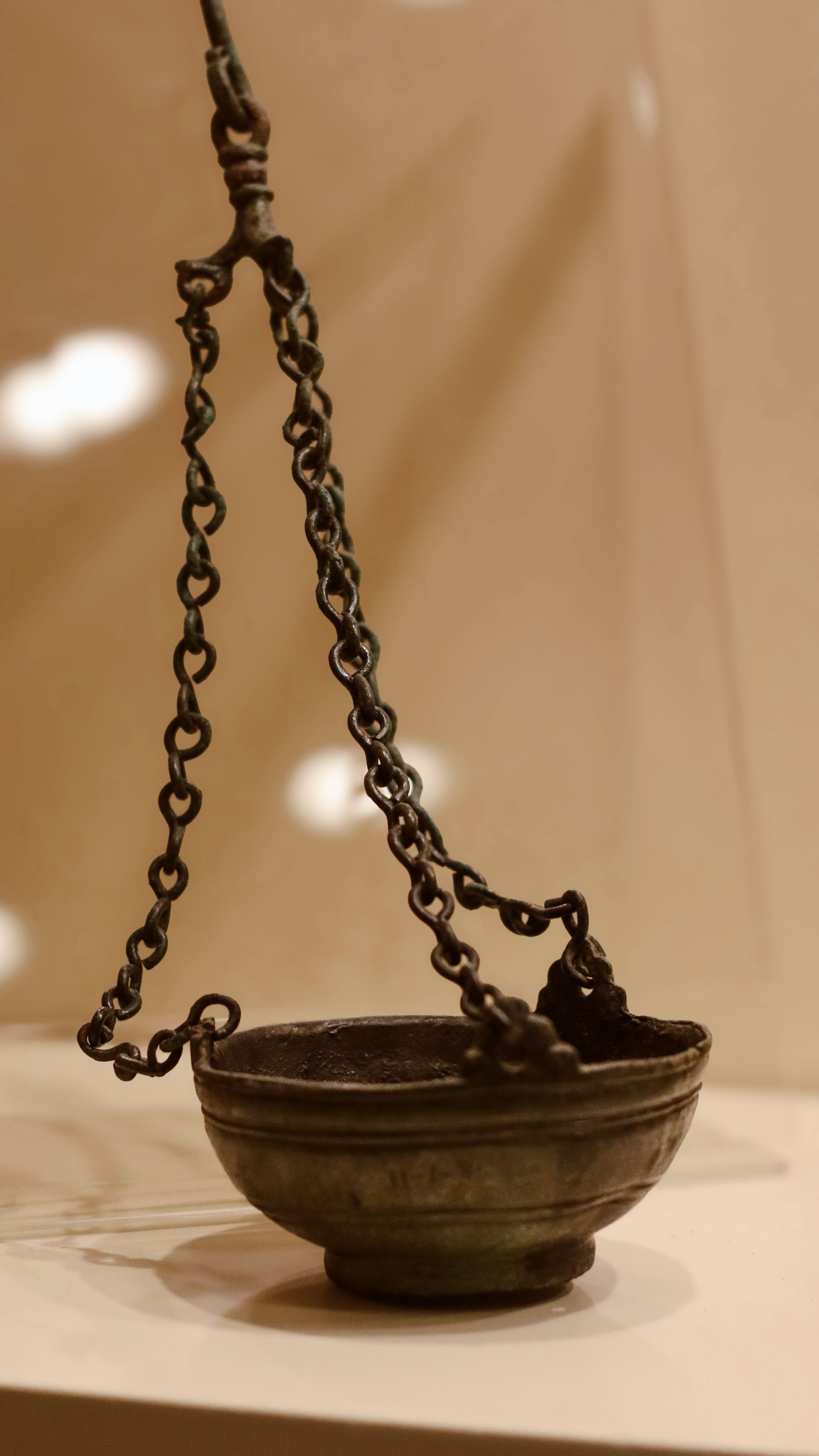 Close-up of an antique metal hanging bowl with a chain, indoors.
