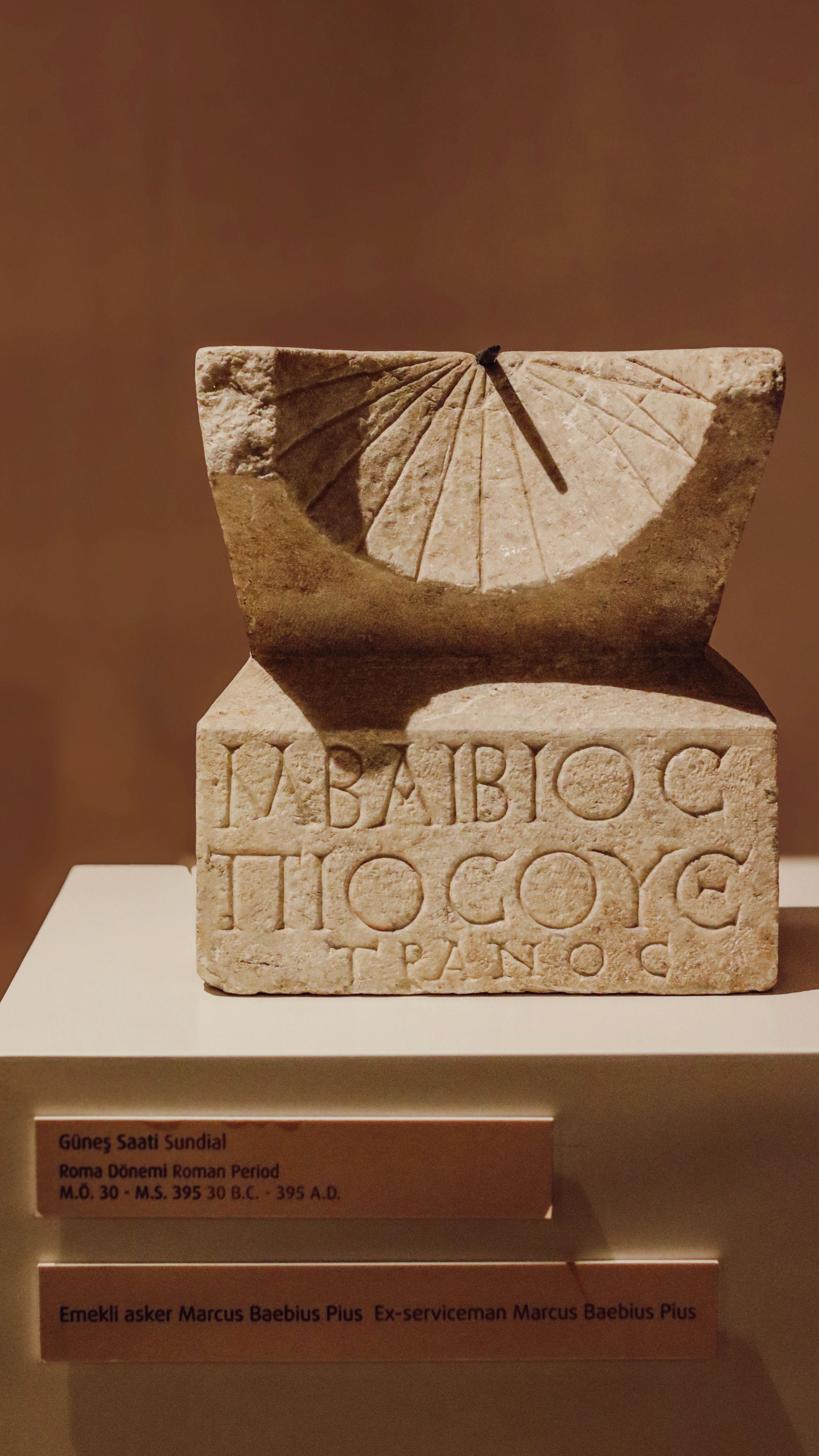 Ancient Roman sundial with inscriptions, displayed in museum.