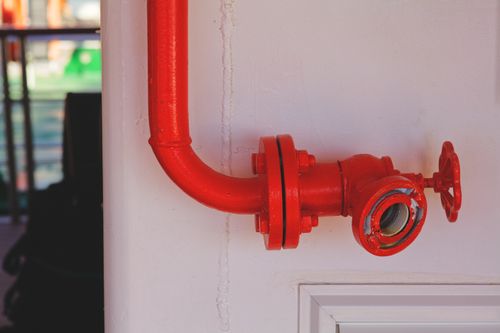 Free Close-up of a vibrant red fire safety valve attached to a white wall. Stock Photo