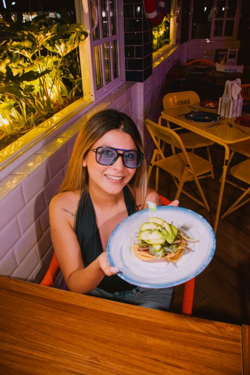 Free Woman holding a gourmet dish indoors at a cozy restaurant, radiating joy and warmth. Stock Photo