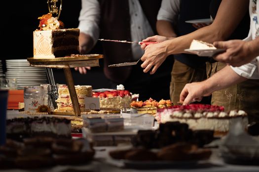 People enjoying a celebration with a selection of decorated cakes and desserts indoors.