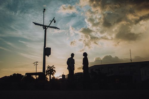 Free Silhouettes of people and a solar lamp post against a dramatic Kaduna sunset sky. Stock Photo