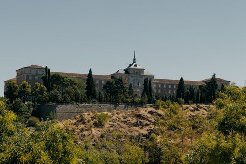 Free Historic Spanish Military Academy building in Toledo surrounded by trees under clear skies. Stock Photo
