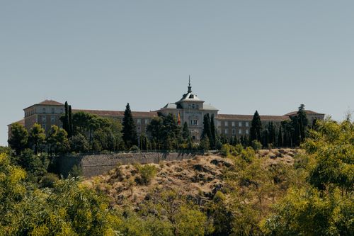 Free Landscape view of the Alcázar of Toledo surrounded by greenery during summer. Stock Photo