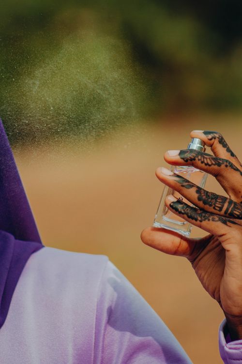 Free A person with henna on hand sprays perfume outdoors, capturing the essence of beauty and culture. Stock Photo