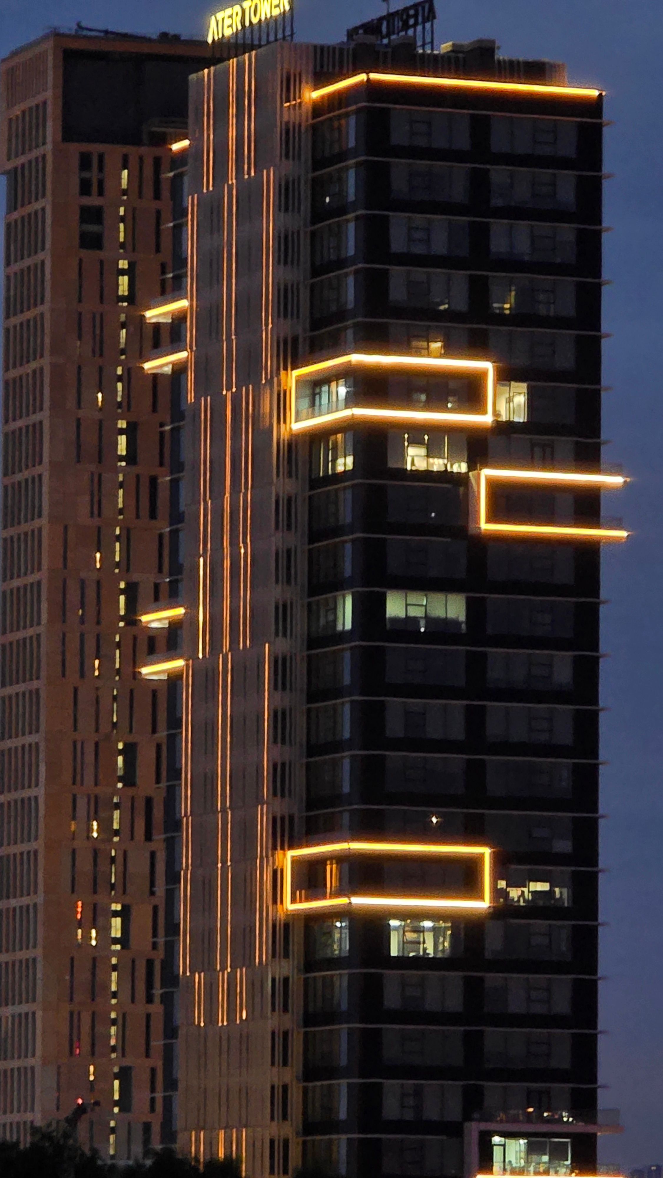 A striking night view of a modern skyscraper with neon lights illuminating its structure.