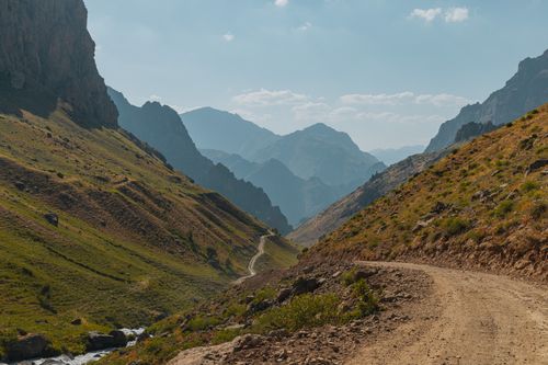 Free Picturesque view of a winding road through a remote mountain valley illuminated by the soft light of sunset. Stock Photo