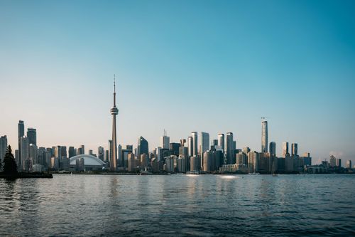 Free Toronto city skyline with CN Tower reflecting on Lake Ontario during a summer sunset. Stock Photo