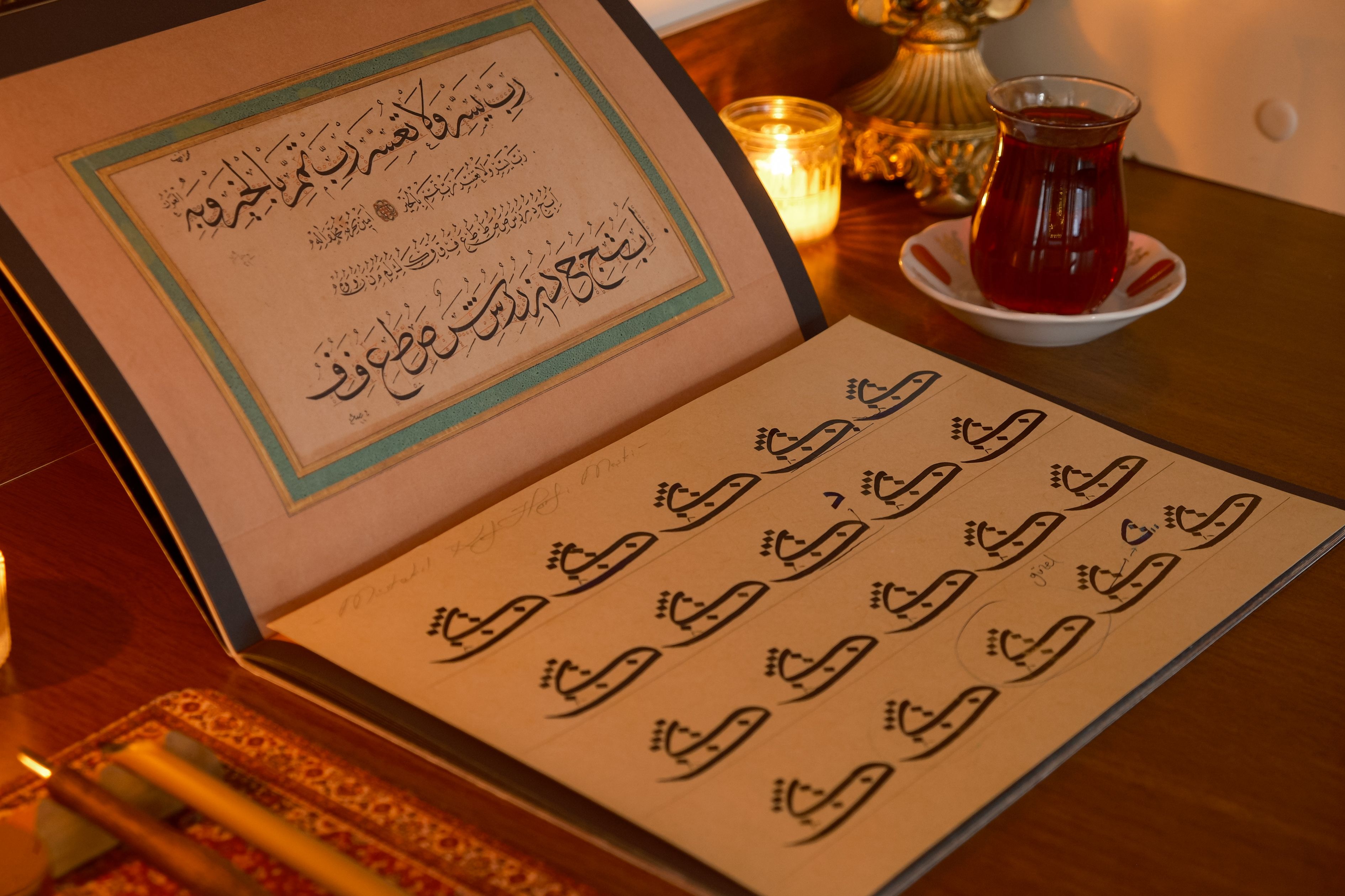 Arabic calligraphy book on a table with tea and candles, beautifully lit.