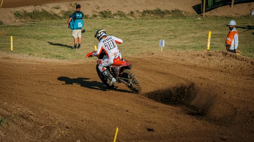 Free Motocross racer taking a sharp turn during a thrilling dirt track race outdoors. Stock Photo