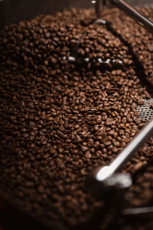 Free Close-up of freshly roasted coffee beans cooling in an industrial roaster, showcasing deep brown hues. Stock Photo
