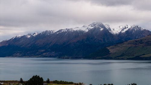Free Snow-capped mountains reflected in a tranquil lake under a cloudy sky in New Zealand's scenic landscape. Stock Photo