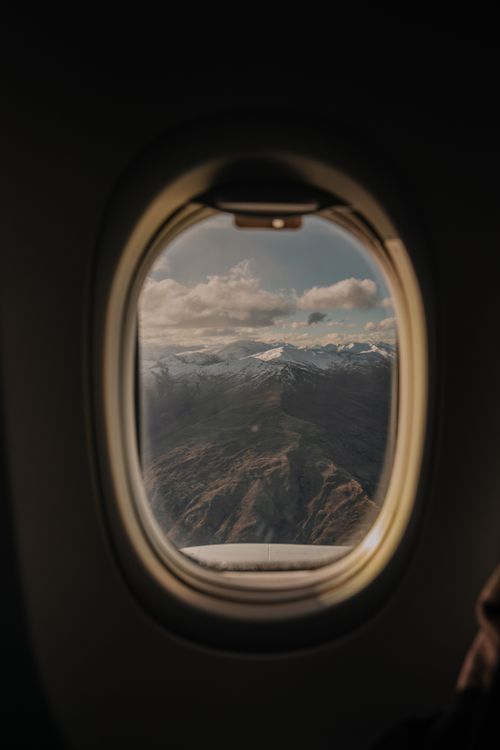 Free Scenic alpine view from airplane window over New Zealand's mountains, showcasing scenic clouds and peaks. Stock Photo