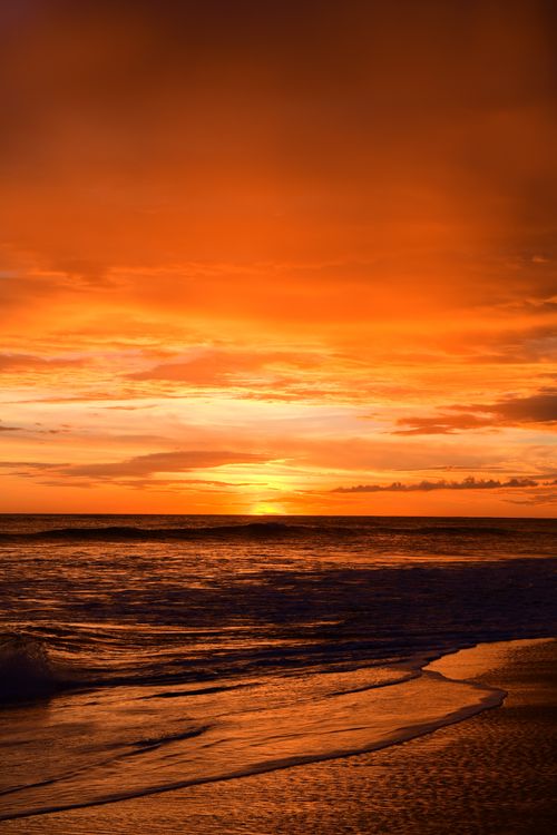 Free Breathtaking sunset at La Boquita Beach, Carazo, Nicaragua, with vibrant orange hues reflecting on the ocean waves. Stock Photo