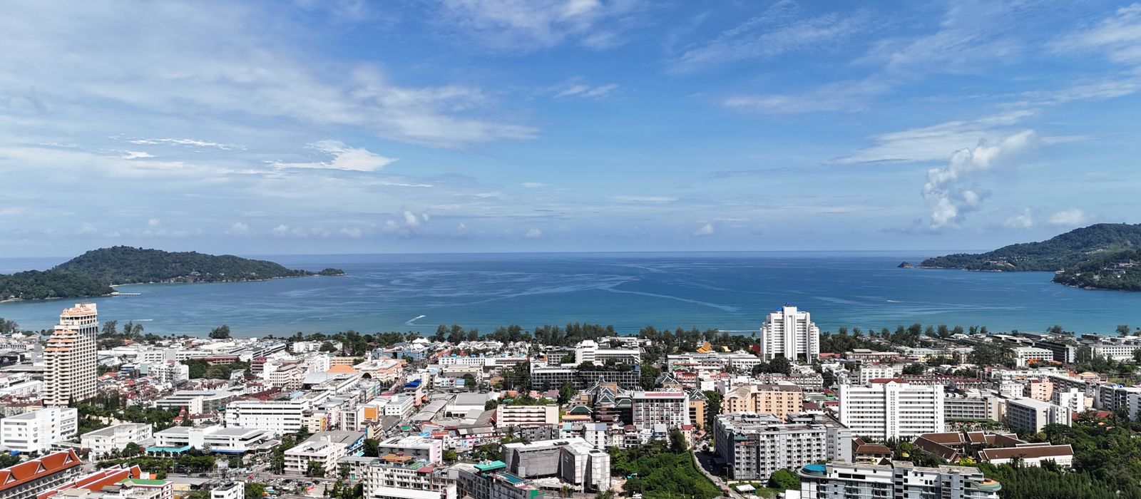 Stunning aerial view of Patong Beach in Phuket, Thailand, with blue skies and cityscape.