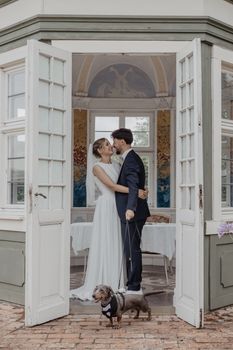 Bride and groom share a romantic moment with their dog at a German estate.