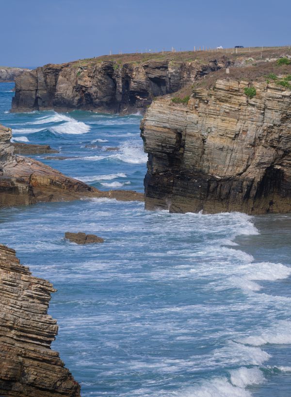 Falaises de flysch stratifiées plongeant dans une eau turquoise, côte de Ribadeo