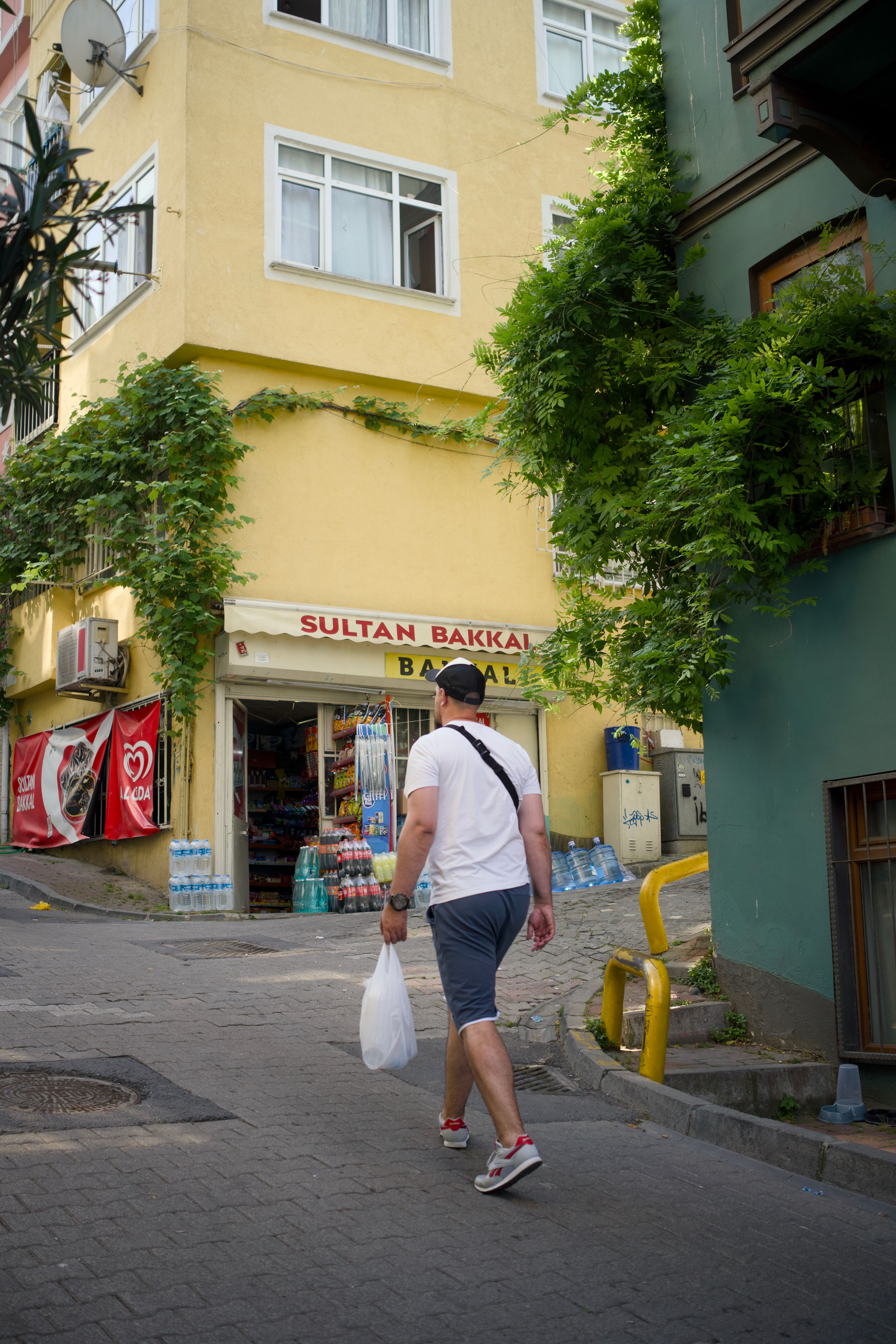 Casually dressed man walking past a shop in İstanbul on a sunny day