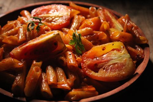 Free Savor a mouthwatering plate of penne pasta with juicy tomatoes, perfectly cooked. Stock Photo