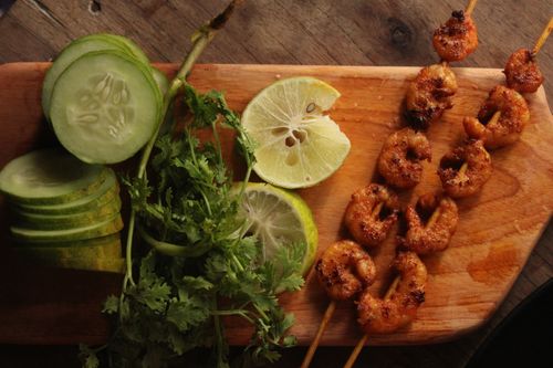 Free Delicious grilled shrimp skewers served with cucumbers and lime on a wooden board. Stock Photo