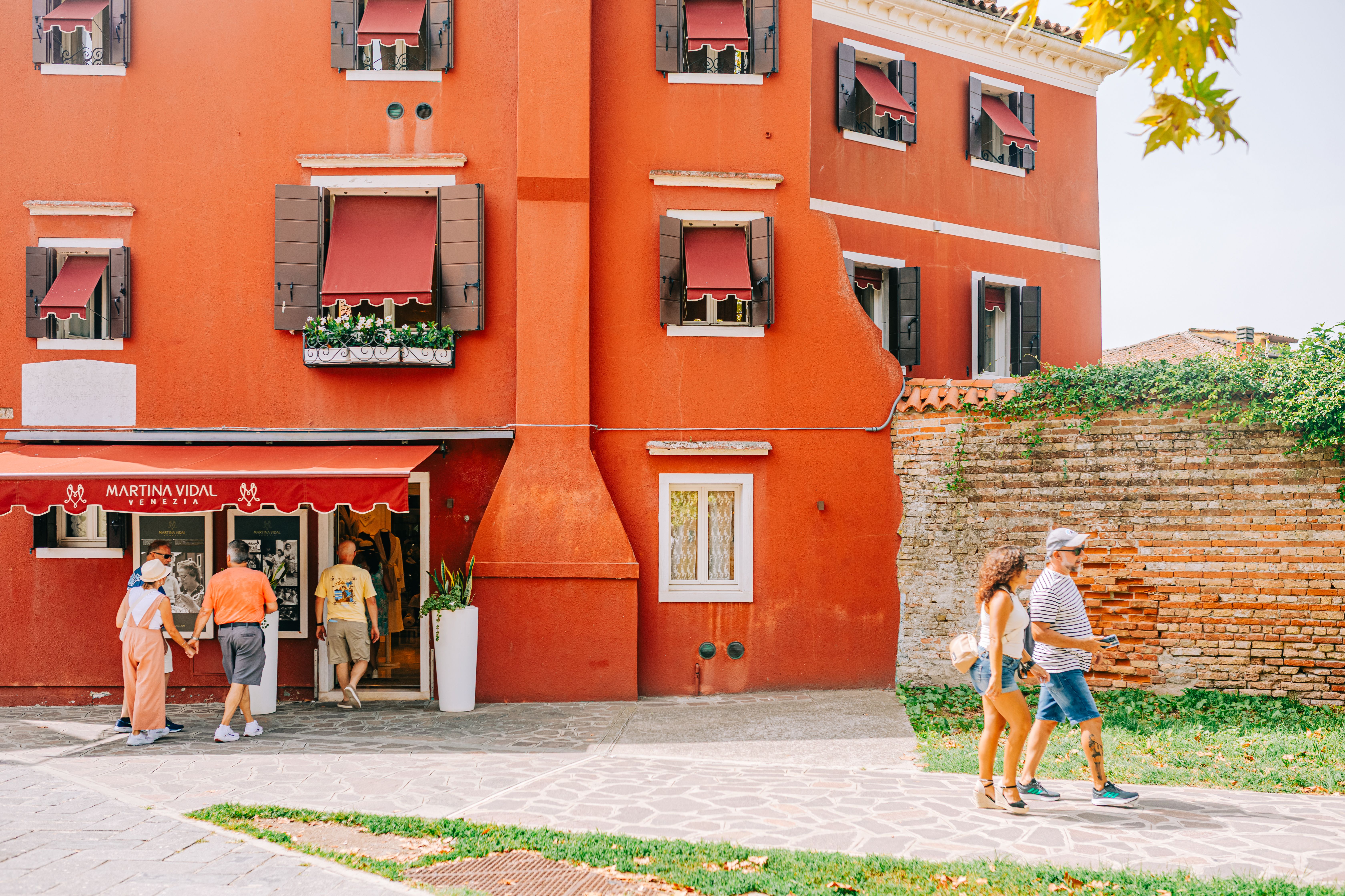 Bright red building in Venice with tourists walking past, capturing Italian charm.