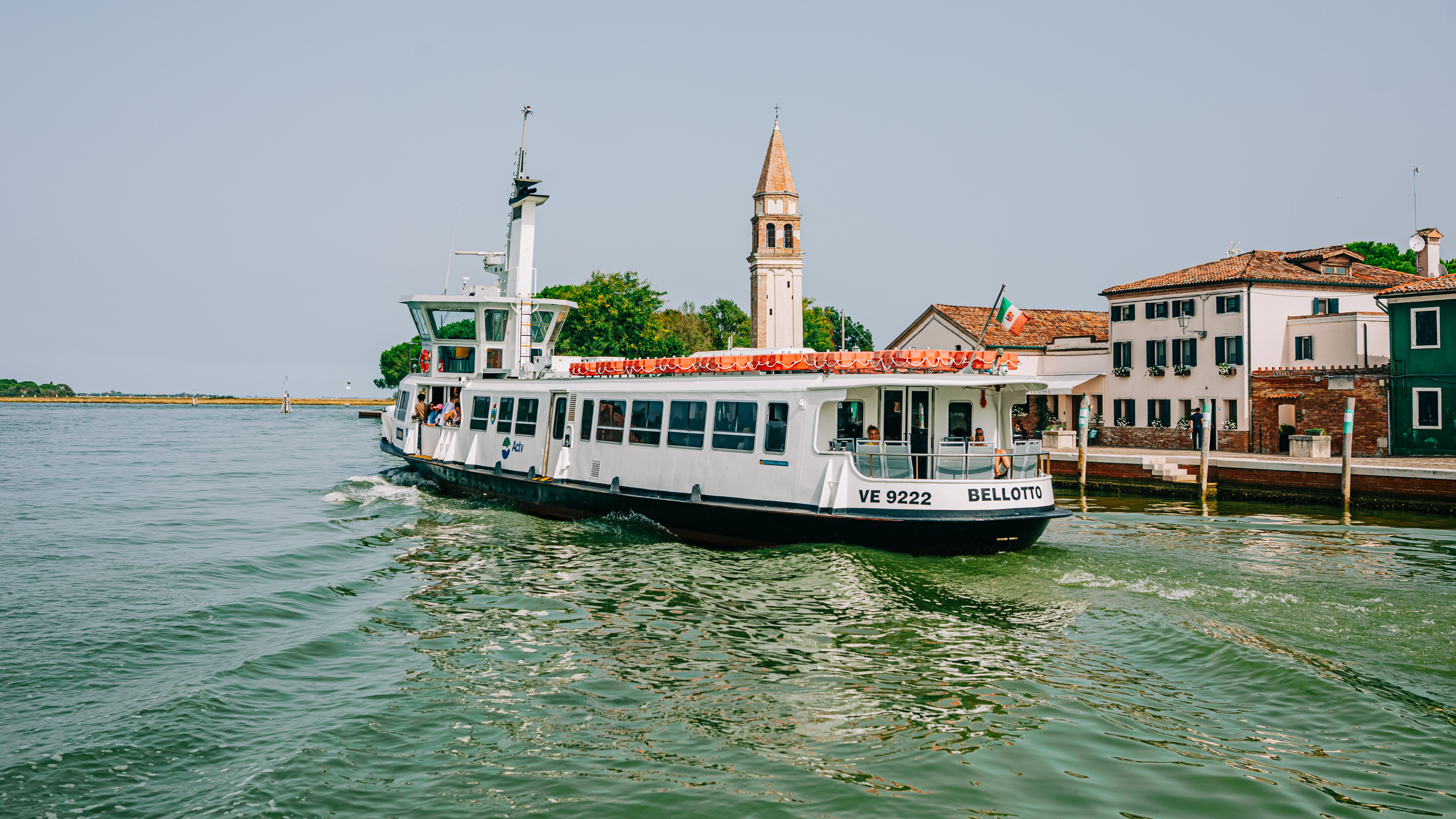 Serene scene of a ferry navigating Venice canals by historic buildings and tower.