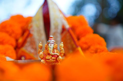 Free A detailed photo of a Lord Ganesha idol amidst vivid orange marigolds, capturing vibrant Hindu culture. Stock Photo