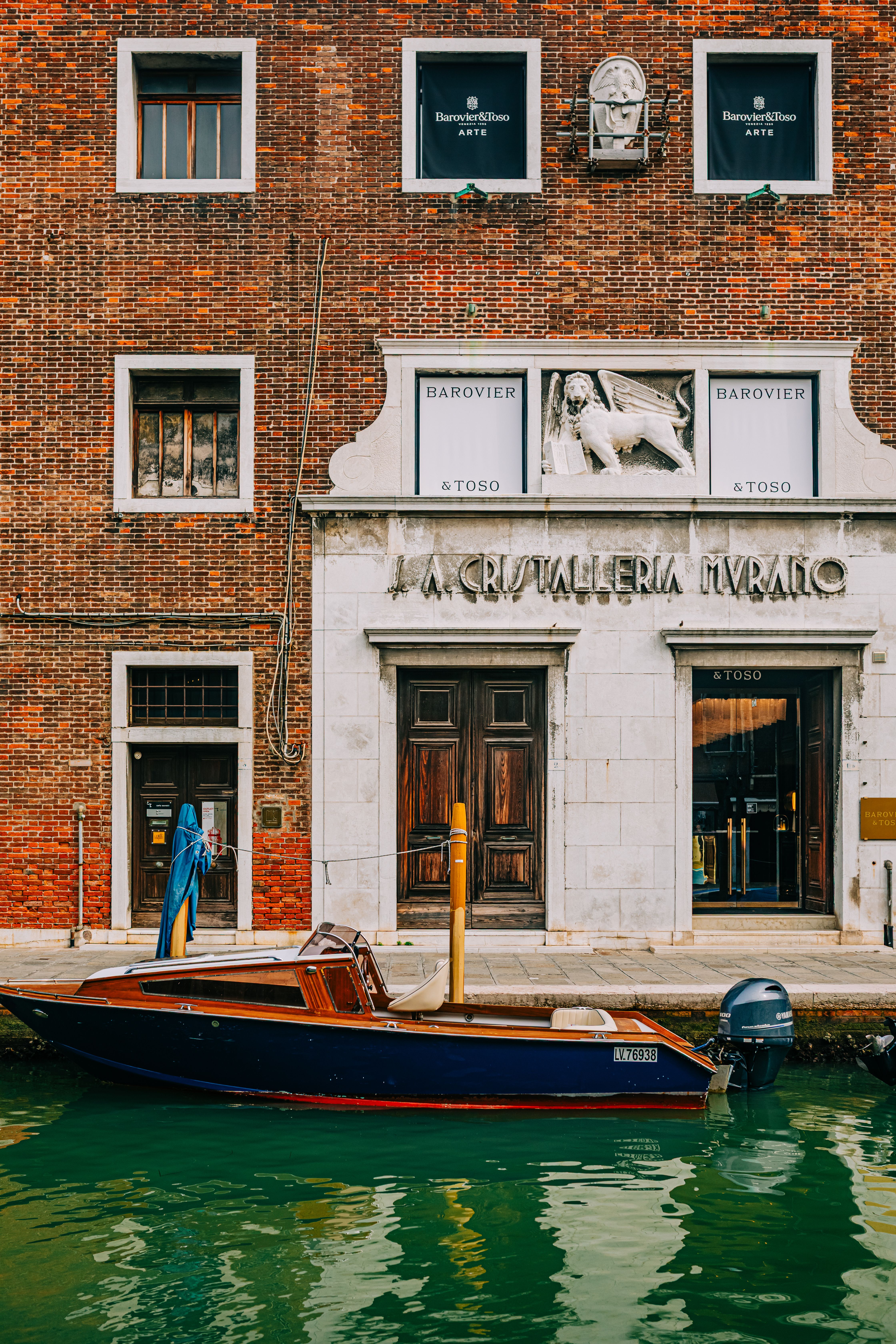 Wooden boat docked by historic brick building on Venetian canal.