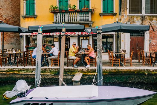 Beautiful canal-side dining at a Venetian restaurant with vibrant architecture.