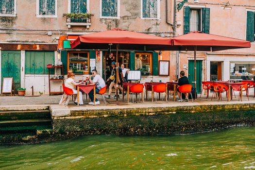 Charming Venice restaurant with outdoor seating by the canal, vibrant and inviting.