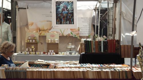 Free A bustling market stall displays various books and artistic items for sale. Stock Photo