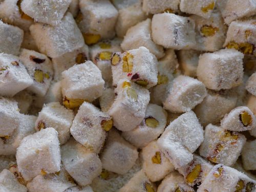 Free A detailed view of Turkish Delight cubes sprinkled with coconut and filled with pistachios, showcasing texture and flavor. Stock Photo