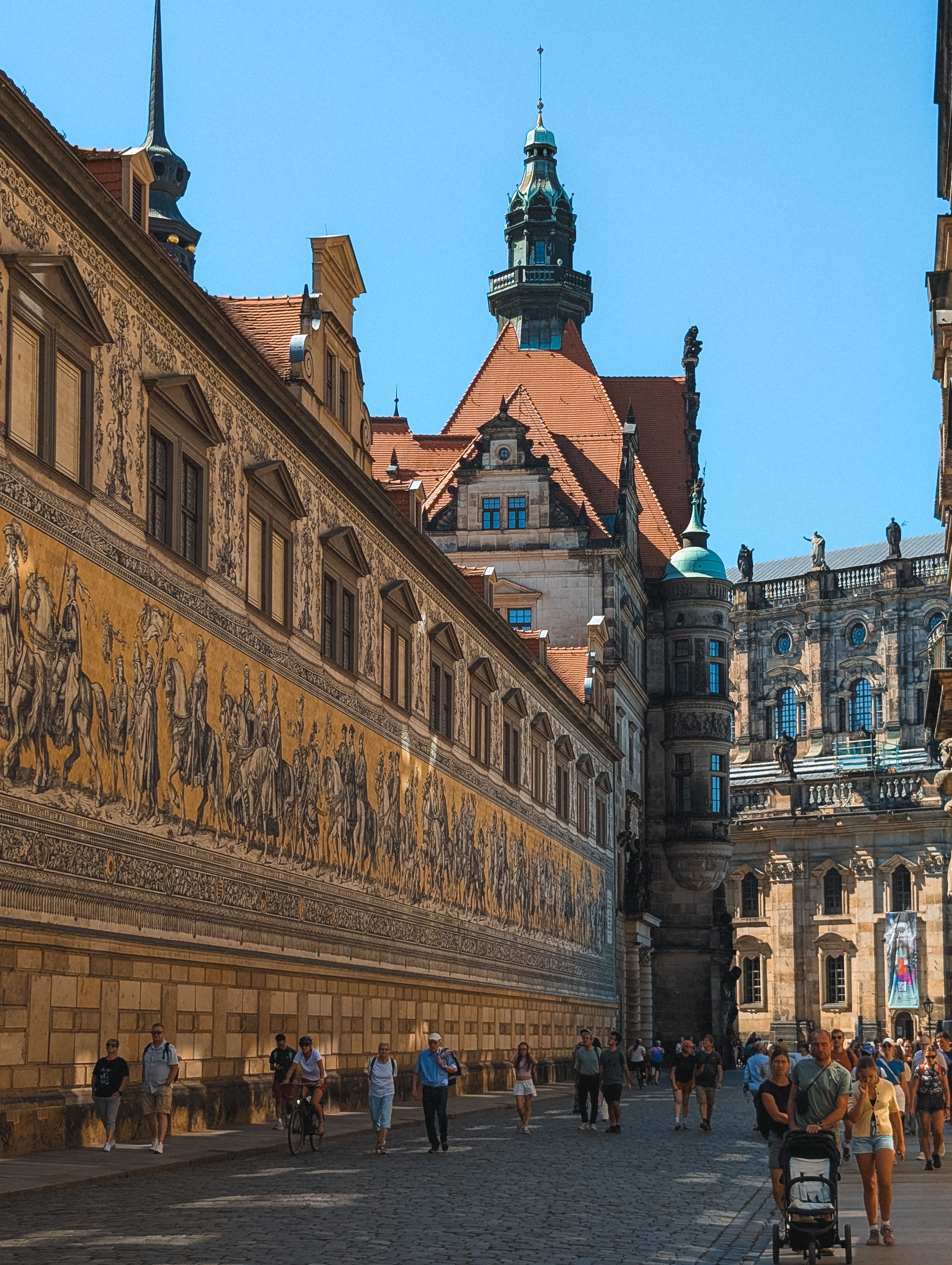 Capture of Dresden's iconic mural and architecture under a clear blue sky, showcasing history and culture.