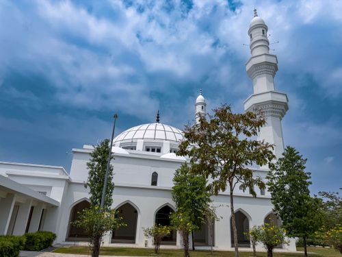 Free Modern white mosque in Seremban, Malaysia, featuring a dome and minaret under a vibrant blue sky. Stock Photo