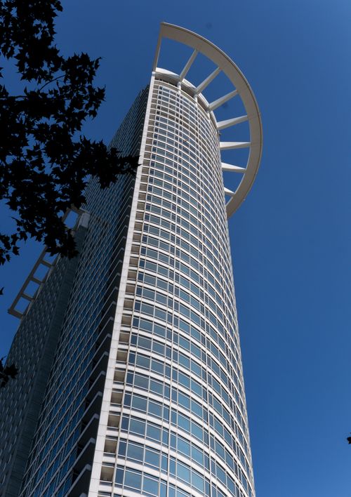 Free A modern skyscraper in Frankfurt featuring a distinctive curved design under clear blue skies. Stock Photo