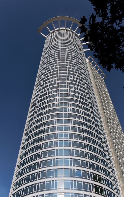 Free Modern skyscraper in Frankfurt, Germany featuring distinct architectural design under a clear blue sky. Stock Photo