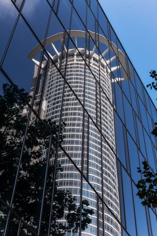 Free Glass facade reflecting a modern skyscraper in Frankfurt, Germany under a clear blue sky. Stock Photo