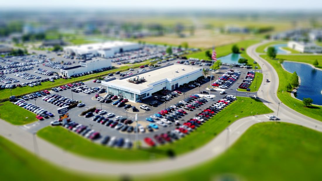 Aerial high-angle view of a car dealership surrounded by parked cars