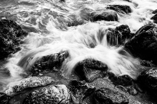 Free Captivating motion of ocean waves crashing over rocky shore, captured in black and white. Stock Photo