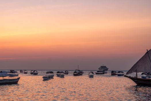 A tranquil view of boats on water at sunset in Tanzania, capturing peaceful colors and reflections.