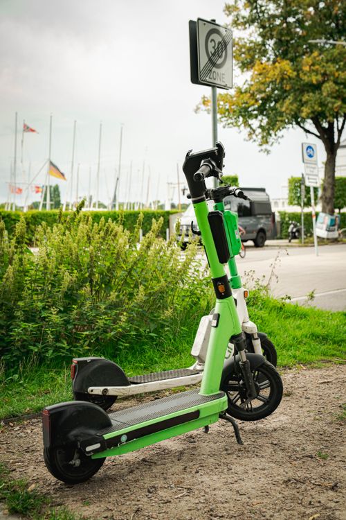 Free Two electric scooters parked near a road with a speed limit sign, showcasing urban mobility in Hamburg. Stock Photo