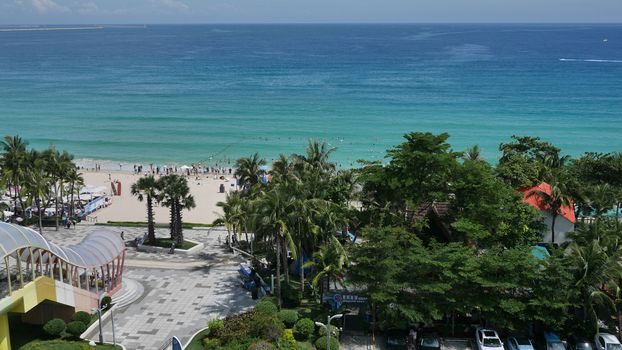 A vibrant beachfront scene in Sanya, Hainan, with lush greenery and clear waters.